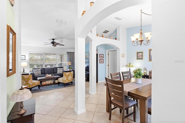 dining space with light tile patterned floors, ceiling fan with notable chandelier, and a high ceiling