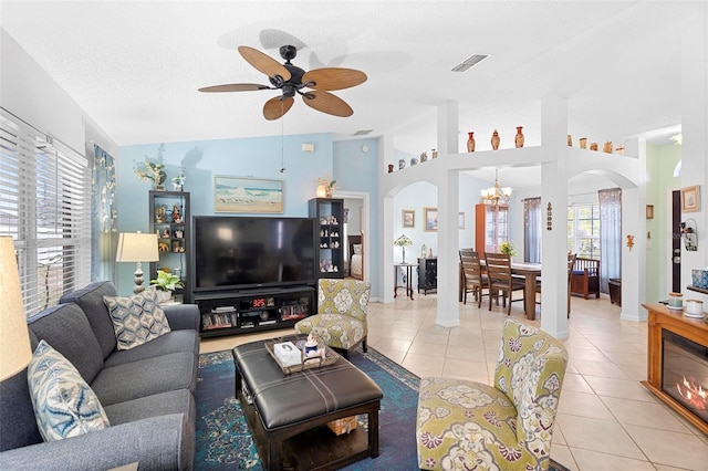 tiled living room with lofted ceiling, ceiling fan with notable chandelier, and a textured ceiling