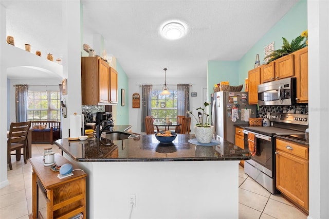 kitchen featuring tasteful backsplash, stainless steel appliances, sink, and hanging light fixtures