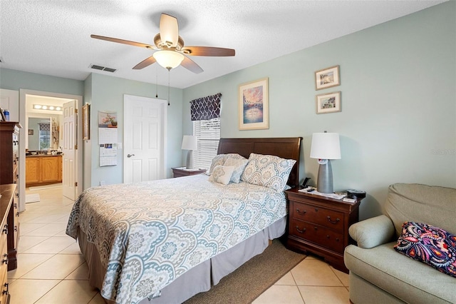 bedroom featuring light tile patterned flooring, ensuite bath, ceiling fan, and a textured ceiling