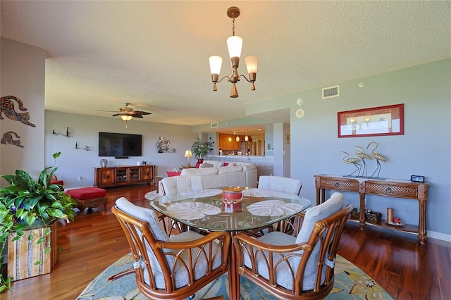 dining area with ceiling fan with notable chandelier, dark hardwood / wood-style floors, and a textured ceiling