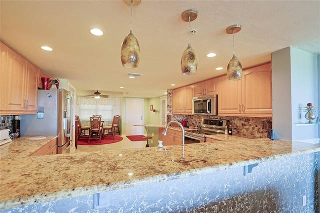 kitchen featuring appliances with stainless steel finishes, light brown cabinetry, decorative light fixtures, decorative backsplash, and ceiling fan