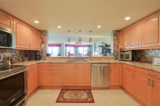 kitchen featuring light stone counters, appliances with stainless steel finishes, decorative light fixtures, and sink