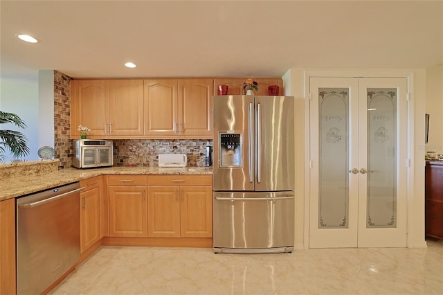 kitchen with french doors, stainless steel appliances, light stone countertops, and backsplash