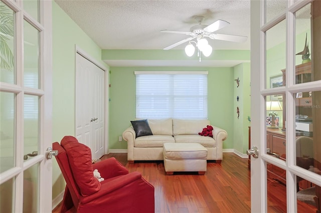 living room with hardwood / wood-style floors, french doors, a textured ceiling, and ceiling fan