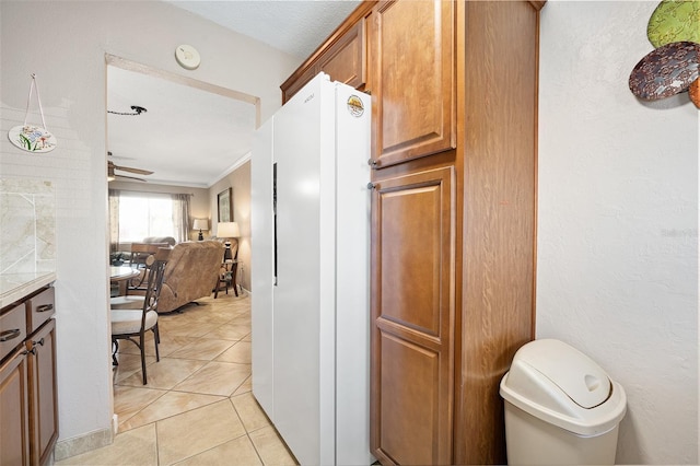 kitchen with ornamental molding, white fridge, and light tile patterned floors