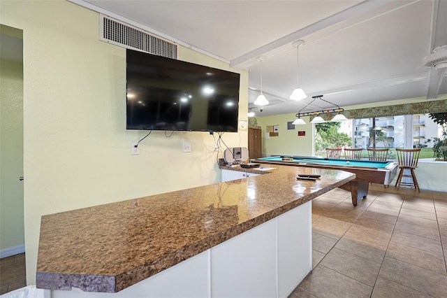 interior space featuring hanging light fixtures, white cabinetry, light tile patterned floors, and kitchen peninsula