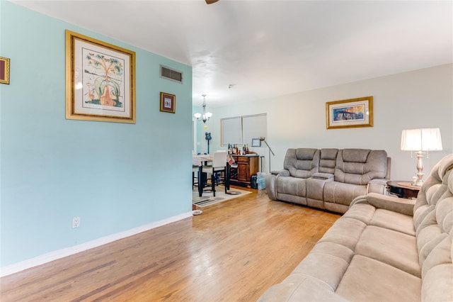 living room with baseboards, visible vents, an inviting chandelier, and light wood-style floors