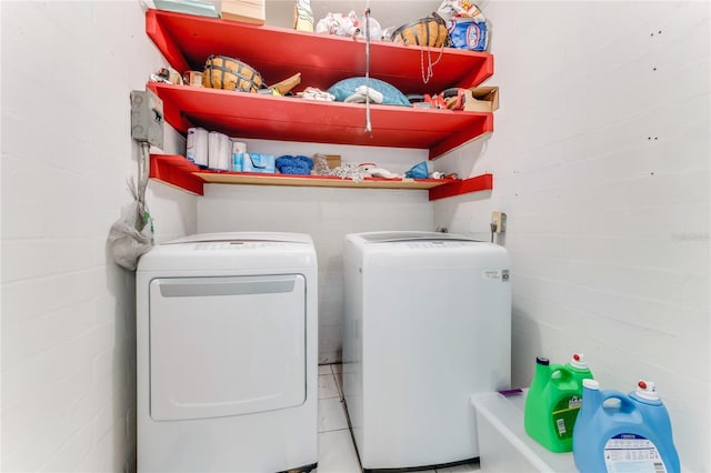 clothes washing area with separate washer and dryer, laundry area, and concrete block wall