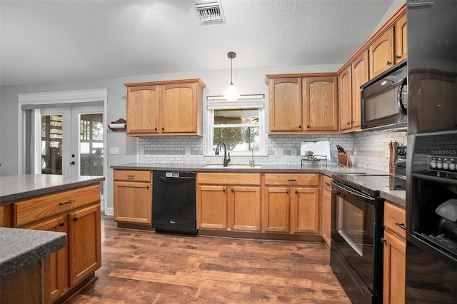 kitchen featuring sink, dark hardwood / wood-style flooring, hanging light fixtures, black appliances, and french doors