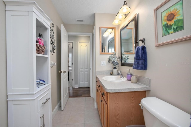 bathroom featuring tile patterned flooring, vanity, a textured ceiling, and toilet