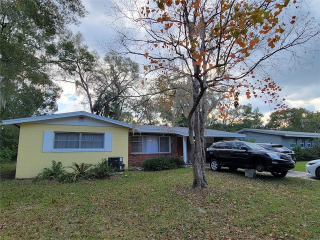 single story home with central air condition unit and a front yard