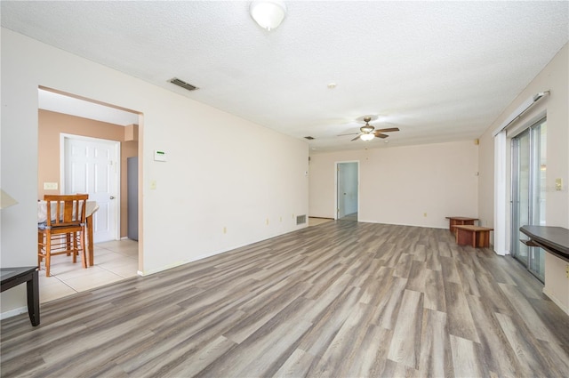 unfurnished room featuring ceiling fan, a textured ceiling, and light wood-type flooring