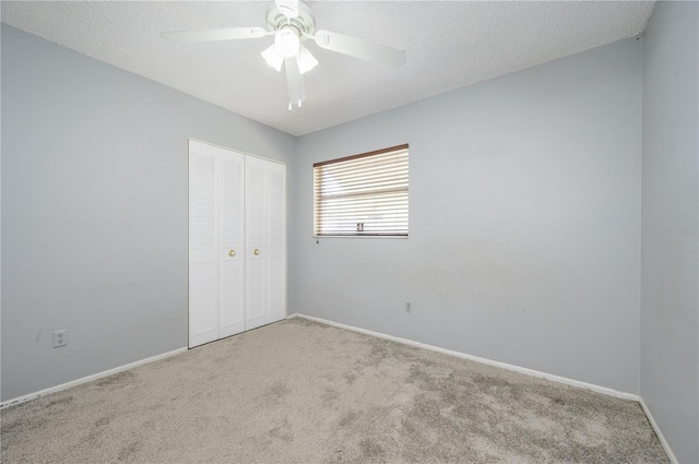 spare room featuring ceiling fan, light colored carpet, and a textured ceiling