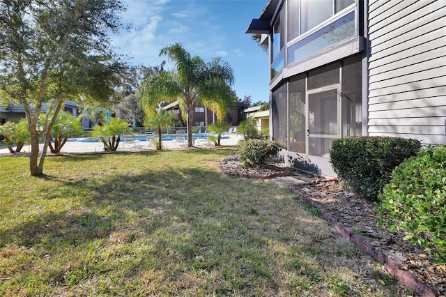 view of yard featuring a sunroom and a community pool