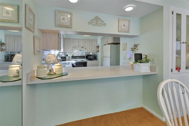 600 N Boundary Ave Unit 114B, Deland, FL 32720 - kitchen with white appliances, a peninsula, under cabinet range hood, light wood-type flooring, and light countertops