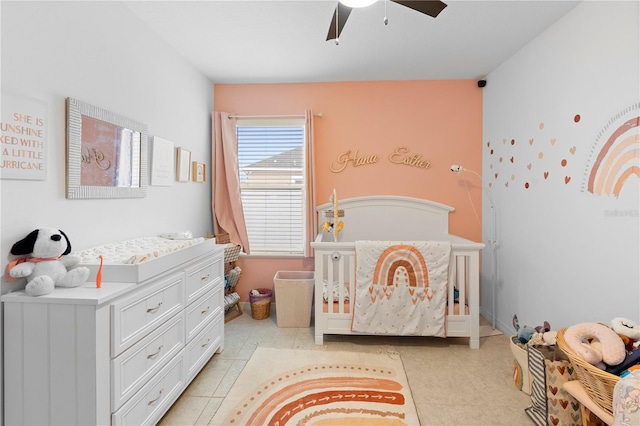 tiled bedroom featuring a crib and ceiling fan