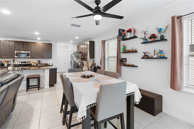 dining space featuring crown molding, ceiling fan, plenty of natural light, and light tile patterned floors