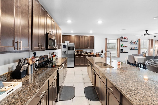 kitchen with sink, light tile patterned floors, ceiling fan, stone counters, and appliances with stainless steel finishes