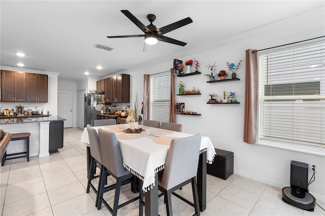 tiled dining area with crown molding and ceiling fan