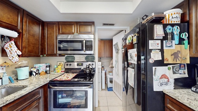 kitchen featuring appliances with stainless steel finishes, light stone countertops, and light tile patterned floors