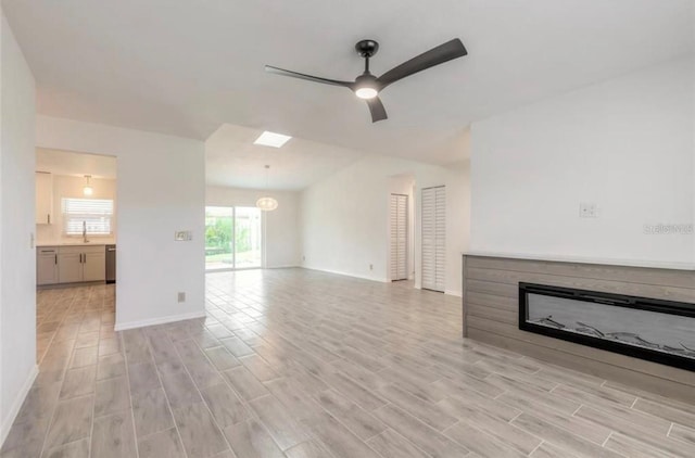 unfurnished living room featuring ceiling fan, sink, and light wood-type flooring