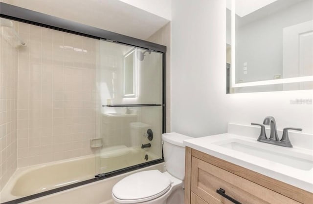 full bathroom with vanity, bath / shower combo with glass door, and toilet