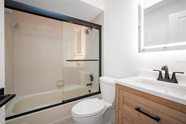 full bathroom with vanity, bath / shower combo with glass door, and toilet