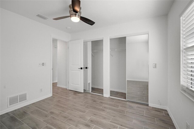 unfurnished bedroom with multiple closets and ceiling fan