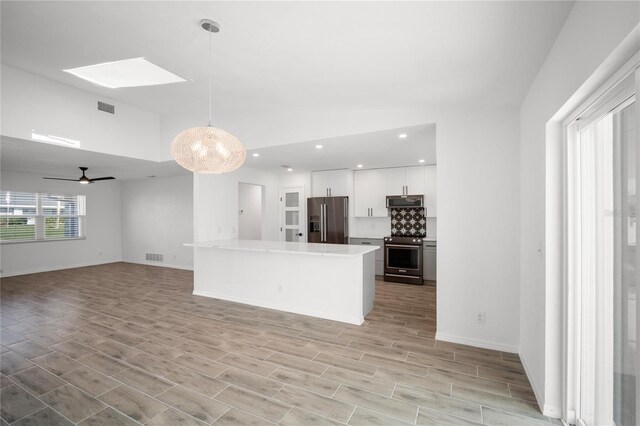 kitchen with light hardwood / wood-style flooring, white cabinetry, hanging light fixtures, stainless steel appliances, and a center island