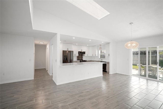 kitchen featuring high quality fridge, white cabinetry, sink, hanging light fixtures, and light hardwood / wood-style floors