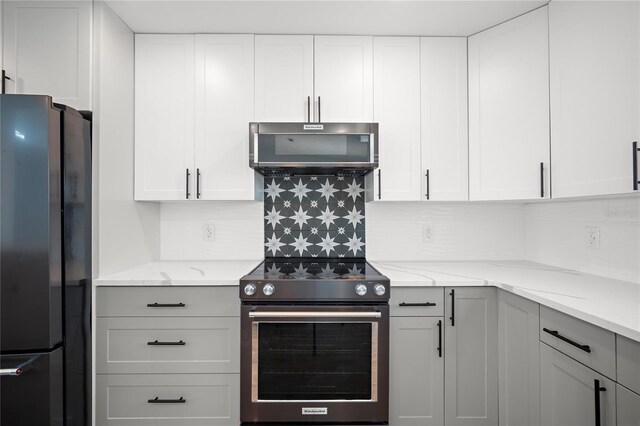 kitchen featuring light stone countertops, black fridge, white cabinets, and stainless steel range with electric stovetop