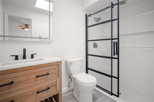 bathroom with vanity, a tile shower, and toilet