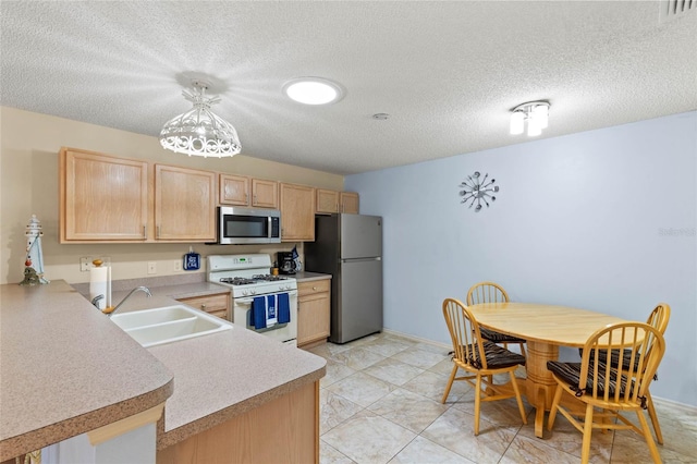 kitchen with pendant lighting, appliances with stainless steel finishes, light brown cabinetry, and sink