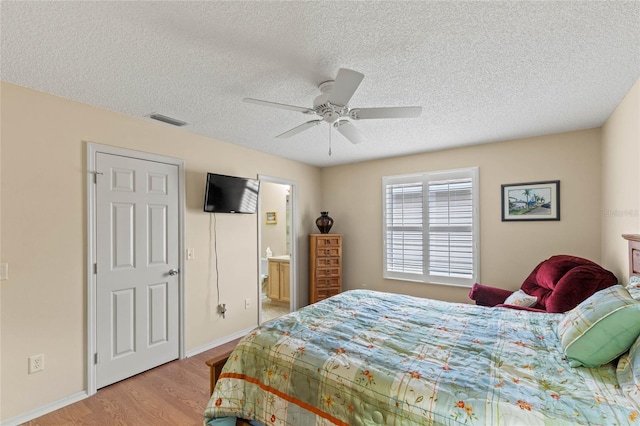 bedroom with ceiling fan, connected bathroom, light hardwood / wood-style floors, and a textured ceiling