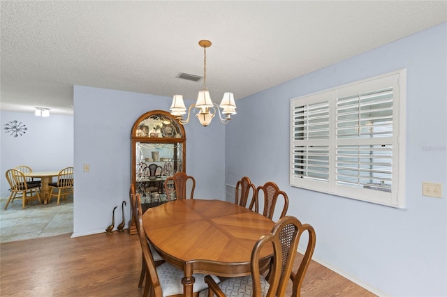 dining room featuring hardwood / wood-style flooring, a notable chandelier, and a textured ceiling