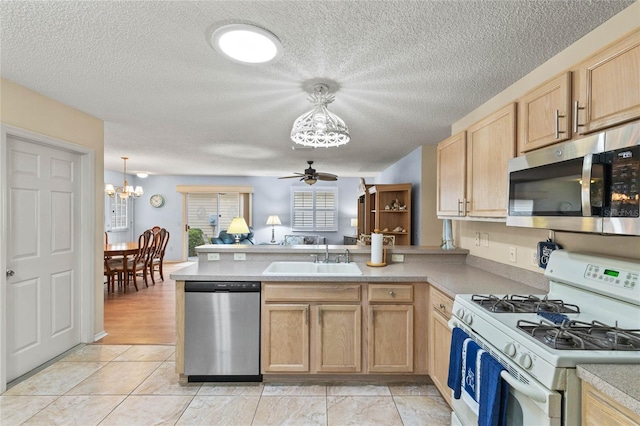 kitchen with sink, decorative light fixtures, kitchen peninsula, and appliances with stainless steel finishes