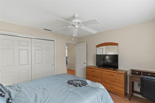 bedroom featuring ceiling fan, light hardwood / wood-style flooring, a closet, and a textured ceiling