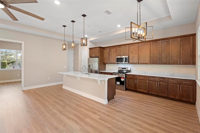 kitchen with stainless steel appliances, an island with sink, a breakfast bar area, and decorative light fixtures