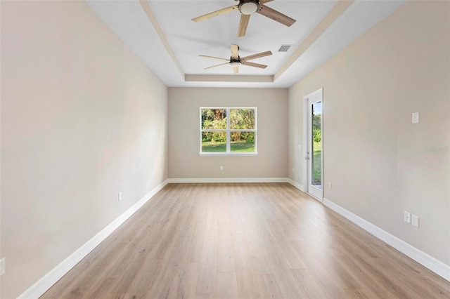 unfurnished room with a raised ceiling, ceiling fan, and light hardwood / wood-style floors