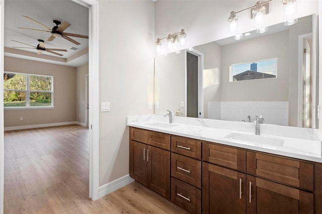 bathroom featuring vanity, wood-type flooring, a raised ceiling, and ceiling fan