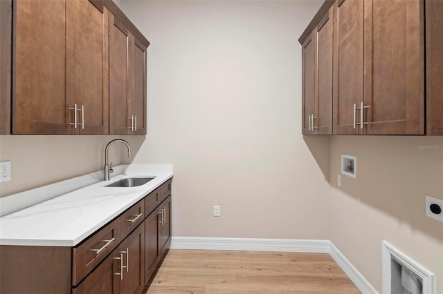 clothes washing area with sink, cabinets, light hardwood / wood-style flooring, washer hookup, and hookup for an electric dryer