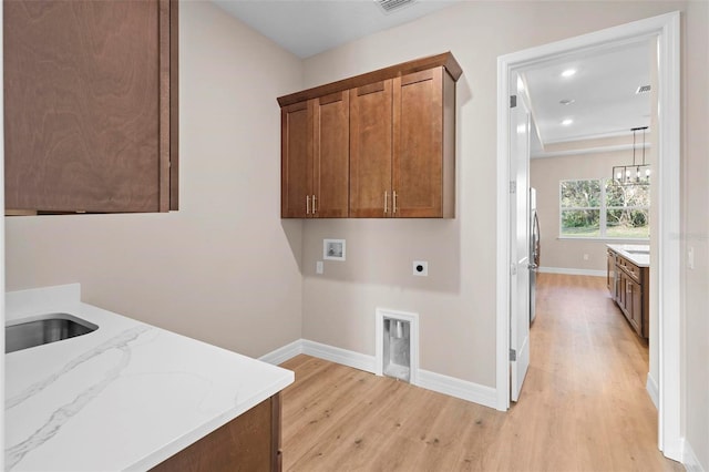 washroom featuring sink, cabinets, hookup for a washing machine, hookup for an electric dryer, and light wood-type flooring