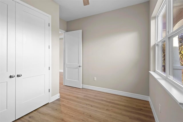 unfurnished bedroom featuring ceiling fan, light hardwood / wood-style floors, and a closet