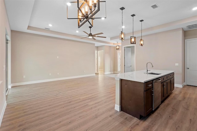 kitchen featuring pendant lighting, sink, light hardwood / wood-style flooring, dishwasher, and a kitchen island with sink