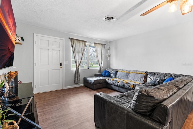 living room featuring hardwood / wood-style flooring, ceiling fan, and a textured ceiling