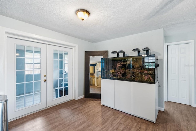 kitchen featuring wood-type flooring, french doors, and a textured ceiling
