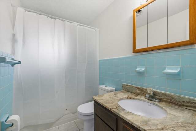 bathroom with vanity, toilet, tile patterned flooring, and tile walls