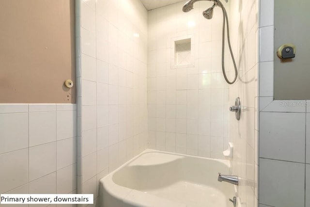 bathroom featuring tiled shower / bath combo and tile walls