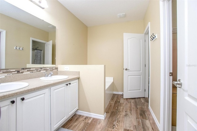 bathroom with hardwood / wood-style flooring, vanity, a tub, and backsplash